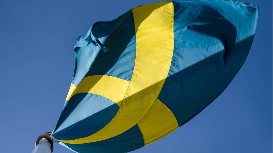Die schwedische Flagge weht vor blauem Himmel im Wind